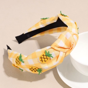 Detail of yellow and white plaid headband with embroidered pineapples and knotted design