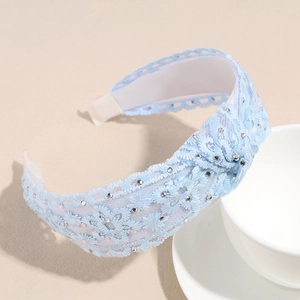 Détail du serre-tête en dentelle bleu clair avec nœud fait main et strass argentés
