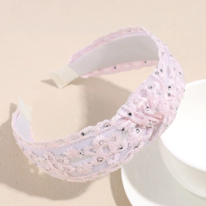 Détail d'un serre-tête en dentelle rose avec broderies et petits strass brillants scintillants