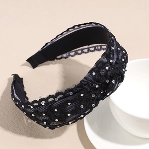 Détail d'un serre-tête en dentelle noire orné de strass argentés pour la coiffure