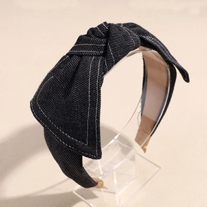 Detailed view of dark blue denim headband with bow knot and white contrast stitching