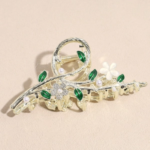 Grande pince à cheveux dorée avec feuilles d'émail vert, cristaux et perles sur fond beige