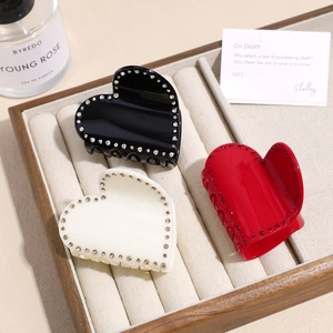 Détail de trois pinces à cheveux en forme de cœur noir, blanc et rouge avec strass fins