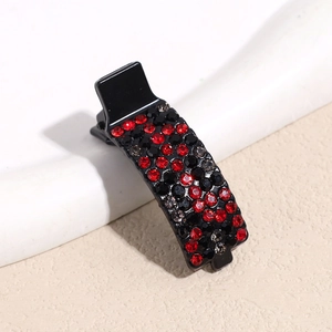 Detail view of a black hair clip with sparkling red and black rhinestones in dot pattern