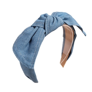 Denim bow headband with white contrast stitching and a knotted design on a white background
