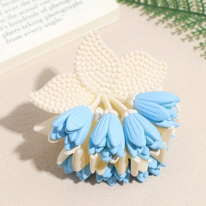 Detailed view of a light blue floral claw clip with matte petals and cream leaf accents