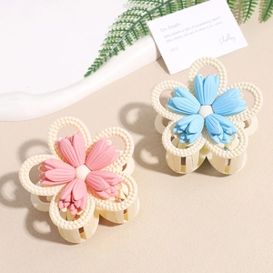 Matte flower hair claw clips with pearl accents in pink and blue colors on a display