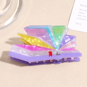Macro detail of the 3D book-shaped hair claw clip with colorful layered acetate edges