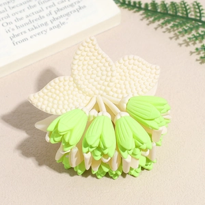 Detail of flower hair claw clip with cream petals and mint green floral accents