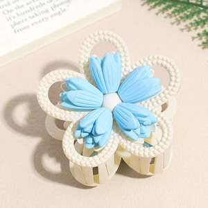 Detail of matte blue flower hair claw clip with pearl textures and sturdy clasp