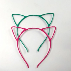Gros plan de serre-têtes oreilles de chat roses et verts avec ruban satiné sur métal