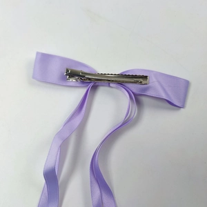Detail of the purple satin bow hair clip featuring a durable silver metal alligator grip