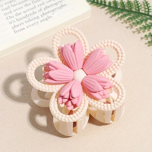 Close-up of a matte pink floral hair claw clip on a minimalist textured table