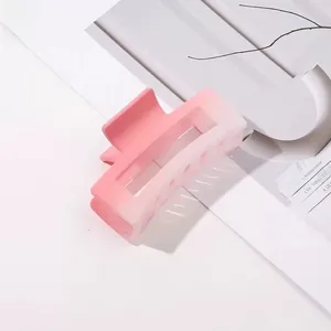 Détail d'une pince à cheveux dégradé rose avec finition mate sur fond minimaliste blanc