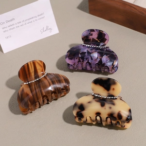 Three elegant acetate hair claws with rhinestones in tortoiseshell and marble patterns