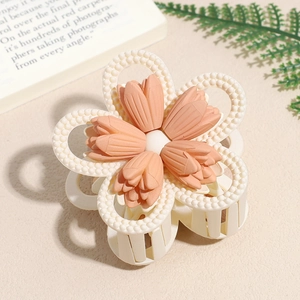 Detail of matte flower hair claw clip with orange petals and cream bead circular trim