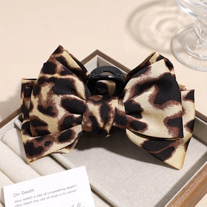 Detail view of large leopard print bow hair claw clip in a warm aesthetic setting