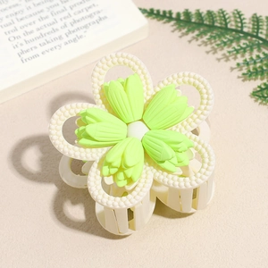 Detailed view of matte green and cream white layered flower claw clip with textured finish