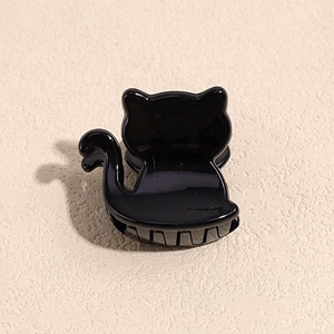 Detail shot of a black acrylic cat-shaped hair claw clip with glossy finish and secure teeth