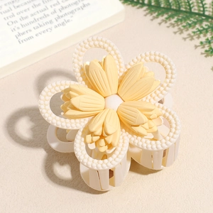 Close-up of matte cream flower hair claw with beaded texture and sturdy grip teeth