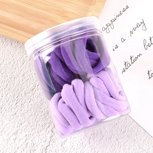 Purple gradient elastic hair ties set in a transparent jar on a wooden tray
