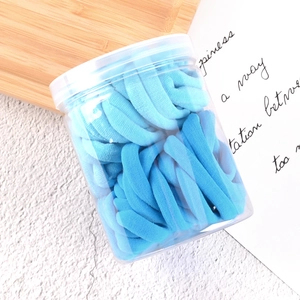 Blue gradient elastic hair ties set in a transparent storage jar on a wooden tray