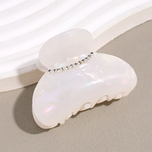 Macro detail of elegant pearlescent acetate hair claw clip with sparkling rhinestones