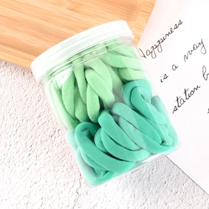 Detail of green gradient elastic hair ties in a transparent cylindrical plastic jar