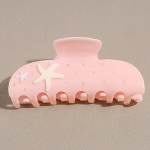Dettaglio della pinza per capelli rosa con stelle marine bianche e strass scintillanti