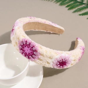 Close-up of crochet floral headband with pink and purple petals on beige knit fabric