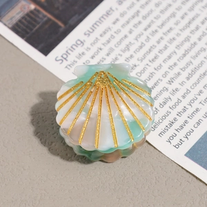 Macro detail of mint green acetate shell hair claw with golden glitter pattern and texture