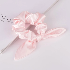 Detailansicht des rosa Satin-Haargummis mit Hasenohren und perlenartigem Glanzeffekt