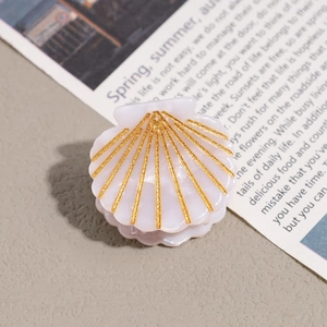 Detail of a shell-shaped acetate hair claw with pink pearlescent finish and gold glitter lines