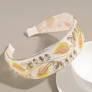 Detailed embroidery of leaves and sequins on a wide cream fabric headband for women
