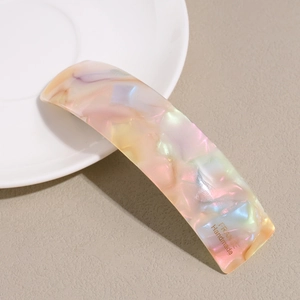 Detail showing the iridescent marble texture and engraved text on the acetate hair clip