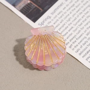 Close-up of a pink pearlescent shell-shaped hair claw with elegant gold glitter stripes