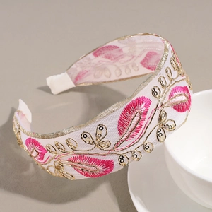Close-up of pink feather embroidery and sequins on a white wide-brimmed headband