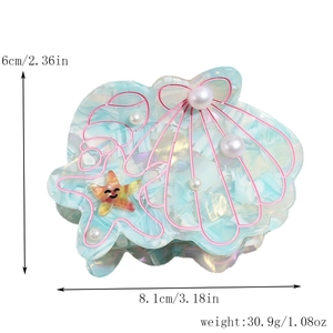 Détail d'une pince à cheveux en forme de coquillage avec étoile de mer et perles