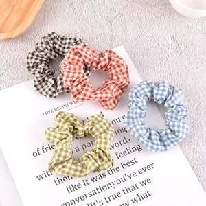 Set of four plaid scrunchies in various colors displayed on a stylish props card