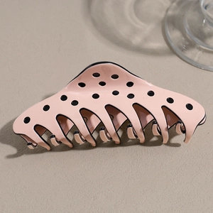 Detailed side view of a glossy pink hair claw clip with black polka dots and dual-row teeth