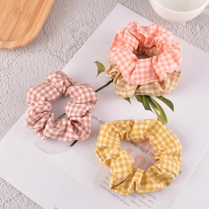 Three-piece set of plaid fabric scrunchies in soft pink, yellow, and beige colors