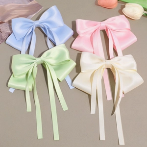 Détail de quatre barrettes à nœuds en satin de couleurs bleu, rose, vert et crème