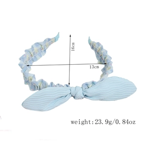 Detail view of a light blue bow headband with dimensions 13x16cm and weight 23.9g