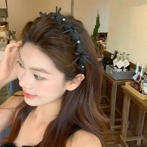 Elegant black bow headband with rhinestones shown on model in a warm cafe setting