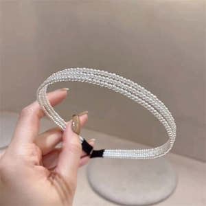 Détail d'un serre-tête à trois rangées de perles blanches avec embouts en tissu noir