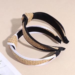 Straw knotted headbands with black and white fabric edges on a minimalist stone background