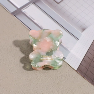 Detail of bear hair claw clip featuring pink green marble pattern and gold handmade text