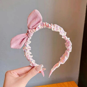 Detailed macro view of a sweet pink pleated fabric headband with a 3D bow accent