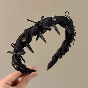 Detail of black headband with bow, rhinestones and spikes in dark aesthetic