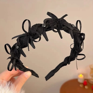 Detail of black satin bow headband featuring mini hair clips and sparkling rhinestones